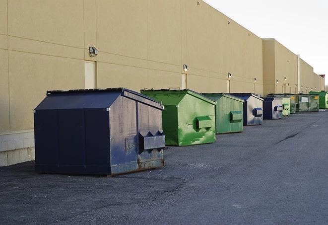 a construction worker unloading debris into a blue dumpster in Ammon